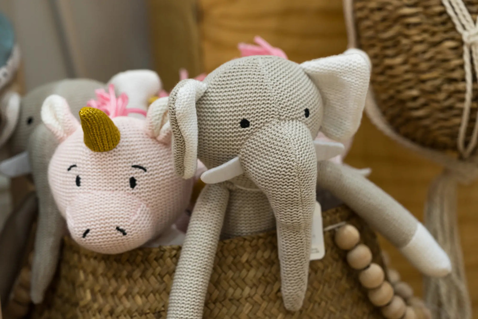 Knitted elephant kids toy in box next to knitted kids pig toy.