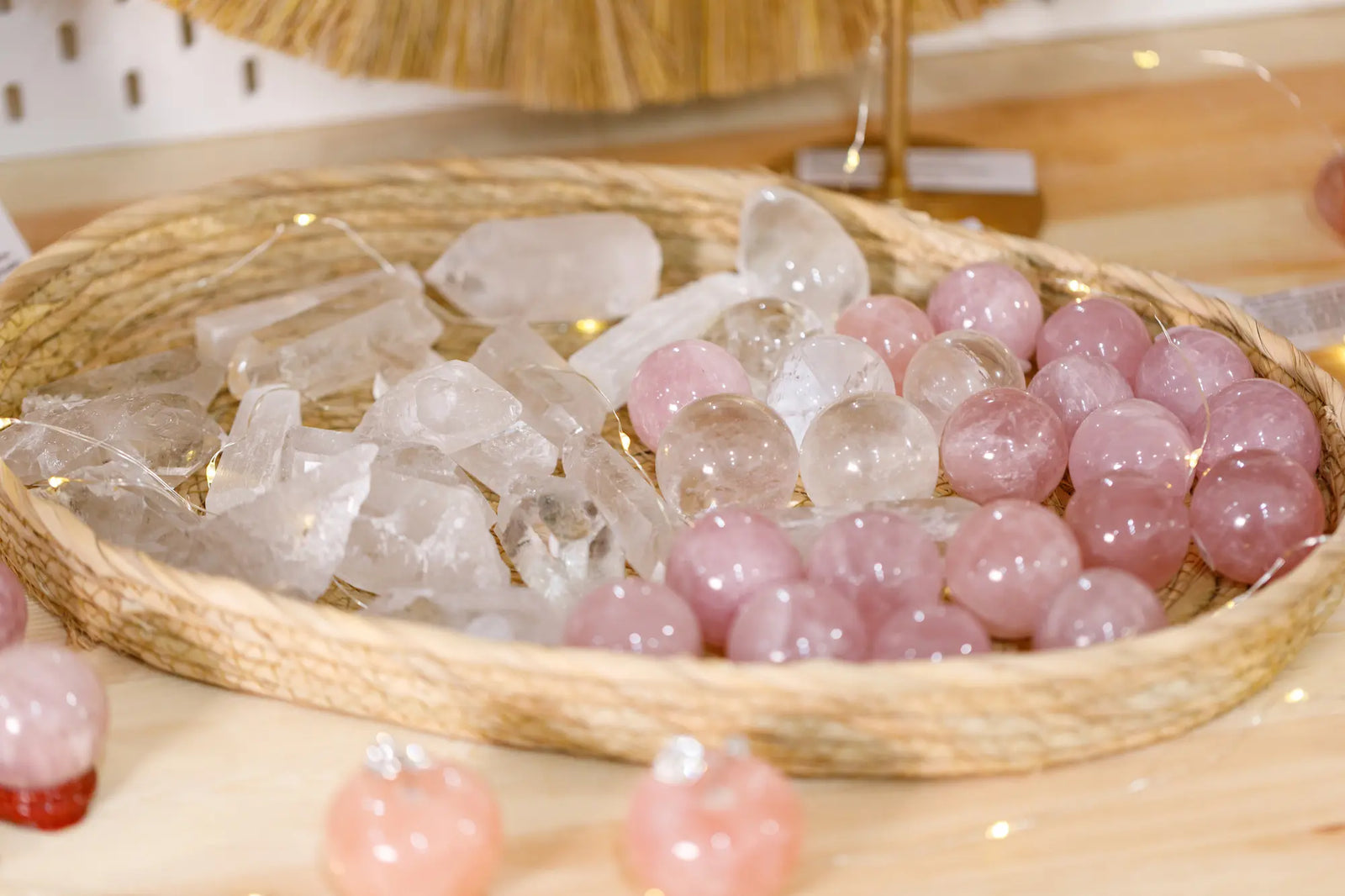 Loose Crystals and Gemstones, both white and pink, sitting in a whicker basket on a wooden table. 